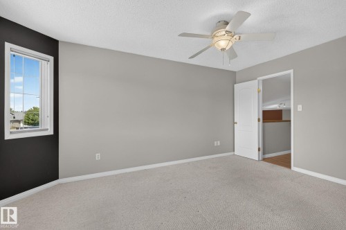 Carpeted room with light gray walls, a contrasting dark accent wall, and a window featuring white trim - 3211 Mcphadden Place Sw, Edmonton, AB - Indoor Photo Showing Other Room