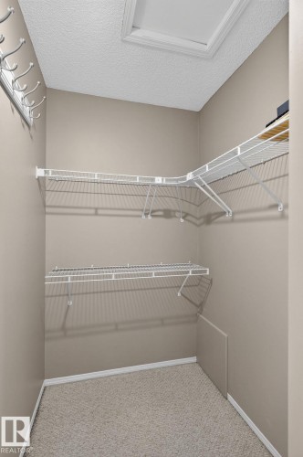 Carpeted closet with L-shaped wire shelving and an additional lower shelf - 3211 Mcphadden Place Sw, Edmonton, AB - Indoor With Storage