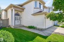 Exterior featuring light-colored siding, an arched transom window above the main entry, a covered porch with a column, an attached garage, and a bay window on the upper level - 3211 Mcphadden Place Sw, Edmonton, AB  - Outdoor 
