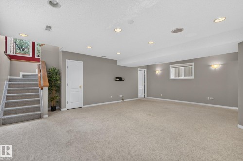 Spacious finished room with light carpet flooring and neutral wall tones - 3211 Mcphadden Place Sw, Edmonton, AB - Indoor