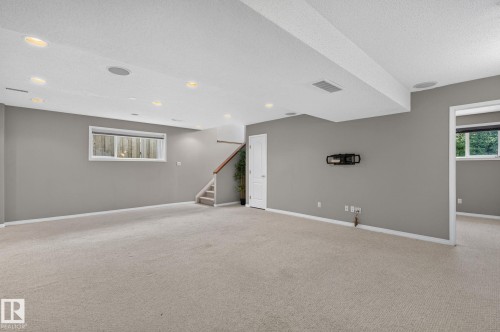 Spacious room featuring neutral carpeting, recessed ceiling lighting, a white painted door, and a built-in speaker system - 3211 Mcphadden Place Sw, Edmonton, AB - Indoor
