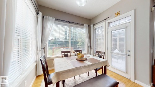 Bright dining area featuring multiple windows with blinds, a glass-paneled door with transom, and wood-finish flooring - 335 62 Street Sw, Edmonton, AB - Indoor Photo Showing Dining Room