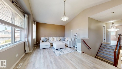 Spacious living area featuring vaulted ceilings, wood-finish flooring, and multiple large windows with blinds - 335 62 Street Sw, Edmonton, AB - Indoor