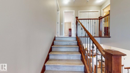 Staircase featuring wood-finish handrails and newel posts with decorative metal balusters - 335 62 Street Sw, Edmonton, AB - Indoor Photo Showing Other Room