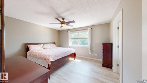 Spacious room featuring light wood-finish flooring, a ceiling fan with integrated lighting, a window with natural light, and neutral wall tones - 335 62 Street Sw, Edmonton, AB - Indoor Photo Showing Bedroom