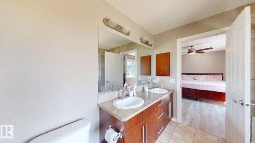 Bathroom featuring a dual vanity with undermount sinks, wood-finish cabinetry, and a neutral countertop - 335 62 Street Sw, Edmonton, AB - Indoor Photo Showing Bathroom