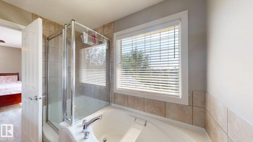 Bathroom featuring a combination shower and tub with glass enclosure, white window blinds, and light-toned wall tiling - 335 62 Street Sw, Edmonton, AB - Indoor Photo Showing Bathroom