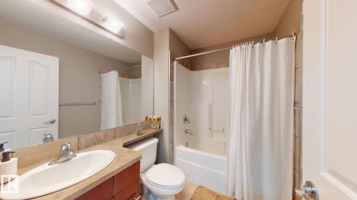 Full bathroom featuring a vanity with a laminate countertop, undermount sink, and wood-finish cabinetry - 335 62 Street Sw, Edmonton, AB - Indoor Photo Showing Bathroom