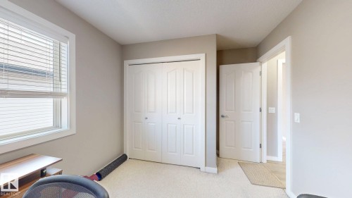 Bright interior room featuring a double-pane window with horizontal blinds, a bi-fold closet, and neutral wall paint - 335 62 Street Sw, Edmonton, AB - Indoor