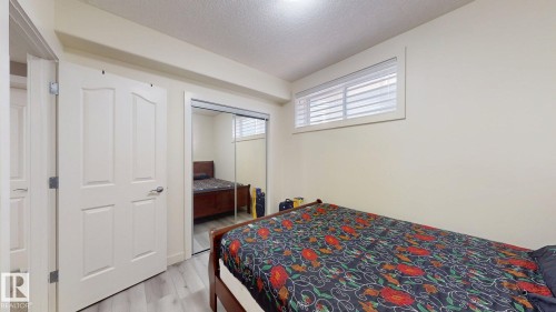 Bright room featuring light wood-finish flooring, a window with horizontal blinds, and a closet with mirrored sliding doors - 335 62 Street Sw, Edmonton, AB - Indoor Photo Showing Bedroom