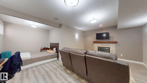Spacious room featuring wood-finish flooring, recessed ceiling lighting, and a window with blinds - 335 62 Street Sw, Edmonton, AB - Indoor With Fireplace