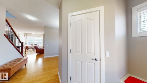 Bright entryway featuring a four-panel door with brushed nickel hardware, hardwood flooring, and a staircase with dark wood handrails and metal balusters - 335 62 Street Sw, Edmonton, AB - Indoor Photo Showing Other Room