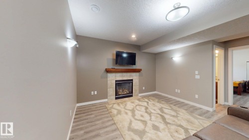 Living area featuring a stone tile fireplace with a wood mantle - 335 62 Street Sw, Edmonton, AB - Indoor With Fireplace