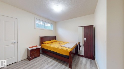 Room featuring light wood-finish flooring, a white paneled door with brushed nickel hardware, and a horizontal window with blinds - 335 62 Street Sw, Edmonton, AB - Indoor Photo Showing Bedroom