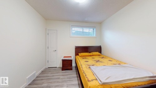 Room featuring light-toned walls, wood-finish flooring, a white interior door, a single window with blinds, and a ceiling-mounted light fixture - 335 62 Street Sw, Edmonton, AB - Indoor Photo Showing Bedroom