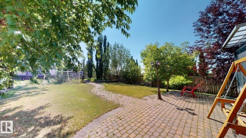 Expansive backyard featuring a paver patio, a winding paver pathway, mature trees, and a manicured lawn - 335 62 Street Sw, Edmonton, AB - Outdoor