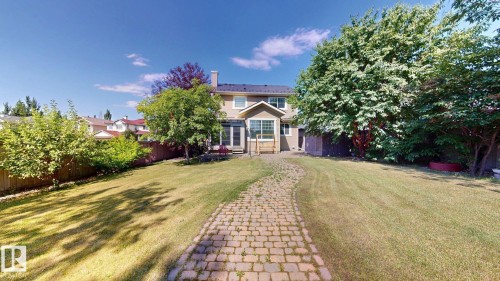 Expansive backyard featuring a green lawn, mature trees, a paver pathway, and wood fencing - 335 62 Street Sw, Edmonton, AB - Outdoor