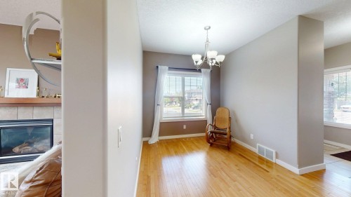 Hardwood flooring extends through this room, illuminated by a window with white blinds and sheer curtains - 335 62 Street Sw, Edmonton, AB - Indoor With Fireplace