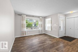 Spacious entry area featuring durable wood-finish flooring, a large picture window, and a frosted glass-paneled entry door - 