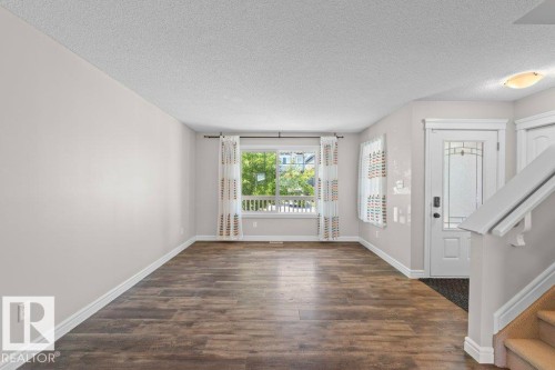 Spacious room featuring wood-finish flooring, light grey walls, and a large window with white trim - 1627 167 Street Sw, Edmonton, AB - Indoor Photo Showing Other Room
