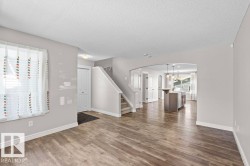 Spacious main living area featuring wood-finish flooring, light grey wall tones, and white trim - 