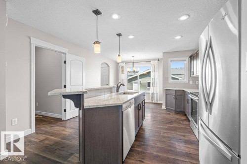 Modern kitchen featuring wood-finish flooring, recessed lighting, and stainless steel appliances - 1627 167 Street Sw, Edmonton, AB - Indoor Photo Showing Kitchen With Upgraded Kitchen