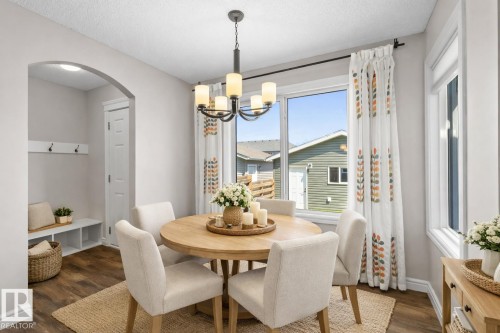 Bright dining area featuring a modern chandelier, wood-finish flooring, and white trim - 1627 167 Street Sw, Edmonton, AB - Indoor Photo Showing Dining Room