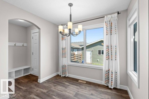 Dining area featuring wood-finish flooring, a modern chandelier with frosted glass shades, and white trim - 1627 167 Street Sw, Edmonton, AB - Indoor Photo Showing Other Room