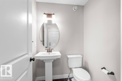 Pedestal sink with bronze-finish faucet, oval mirror, and overhead lighting fixture - 
