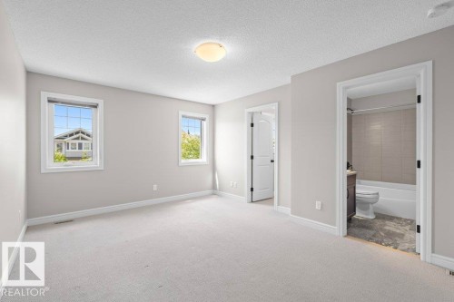 Spacious room with light-toned carpeting, two windows, and a flush-mount ceiling light - 1627 167 Street Sw, Edmonton, AB - Indoor Photo Showing Other Room