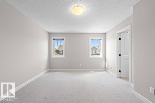 Carpeted room featuring two windows with white trim, a semi-flush mount ceiling light, light gray wall paint, and white baseboards - 1627 167 Street Sw, Edmonton, AB - Indoor Photo Showing Other Room