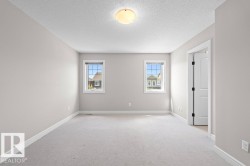 Carpeted room featuring two windows with white trim, a semi-flush mount ceiling light, light gray wall paint, and white baseboards - 