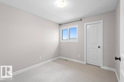 Carpeted room featuring a white interior door with black hardware, a window with white trim, light gray walls, and white baseboards - 