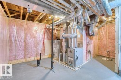 Unfinished basement space featuring exposed wood framing, ceiling joists, and a concrete floor - 
