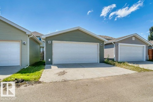 Two detached garages featuring horizontal siding, white overhead doors, and asphalt shingle roofs - 1627 167 Street Sw, Edmonton, AB - Outdoor With Exterior