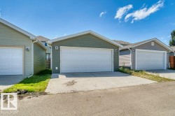 Two detached garages featuring horizontal siding, white overhead doors, and asphalt shingle roofs - 
