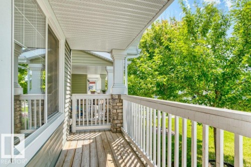Covered porch featuring wood-finish flooring, white railing, stone column accents, and vinyl siding - 1627 167 Street Sw, Edmonton, AB - Outdoor With Exterior