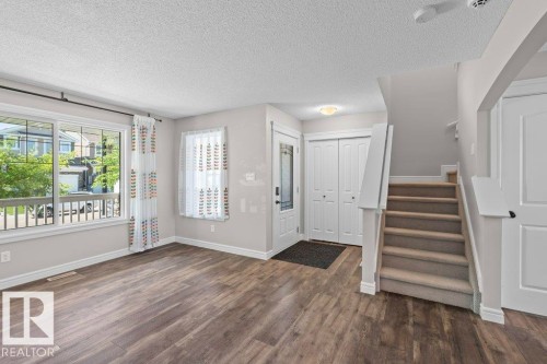 Foyer entry with wood-finish flooring, two-panel bifold closet doors, and staircase featuring carpeted treads and white risers - 1627 167 Street Sw, Edmonton, AB - Indoor Photo Showing Other Room