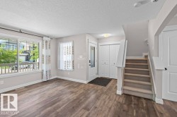 Foyer entry with wood-finish flooring, two-panel bifold closet doors, and staircase featuring carpeted treads and white risers - 