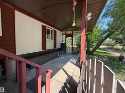 Covered front porch featuring a brown metal roof, red painted wood railings, and a concrete patio - 