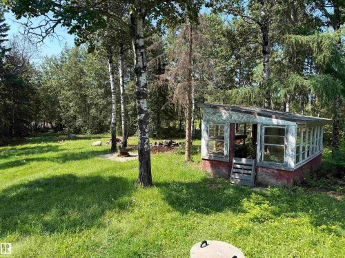 Garden structure featuring multiple window panels and a wood-slat door, set within a grassy area - # 501  11131 Twp Rd 600, Rural St. Paul County, AB - Outdoor