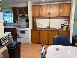 Kitchen space featuring wood-finish flooring, two-tone cabinetry with dark brown and lighter wood finishes, and a window with a valance - 