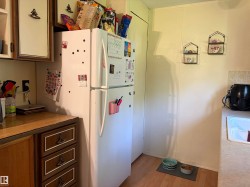 Kitchen area featuring wood-finish flooring, white panel walls, and a white refrigerator - 