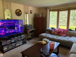 Carpeted living area featuring a large window array, beige wall finishes with decorative accents, and a built-in wooden cabinet - 