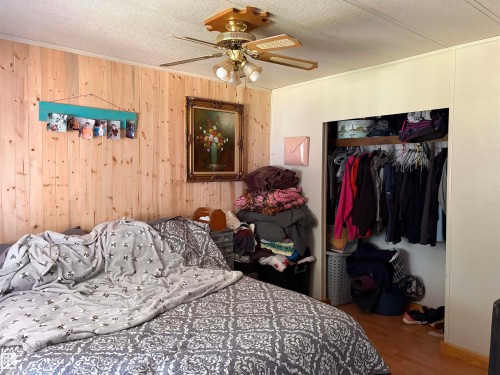 Interior room featuring wood-plank accent wall and built-in closet with shelving - # 501  11131 Twp Rd 600, Rural St. Paul County, AB - Indoor Photo Showing Bedroom