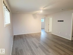 Spacious room featuring wood-finish flooring and light gray walls - 