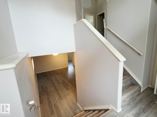 Interior staircase featuring wood-finish treads and risers, white handrails, and neutral wall tones - 123 Rue Masson, Beaumont, AB - Indoor Photo Showing Other Room