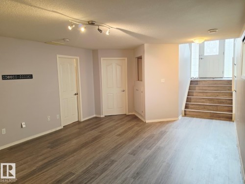 Spacious lower-level area with wood-finish flooring, neutral wall tones, and recessed lighting - 123 Rue Masson, Beaumont, AB - Indoor Photo Showing Other Room