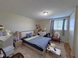 Bedroom featuring a window with blinds, wood-finish flooring, and light-toned walls - 