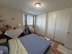 Bedroom featuring wood-finish flooring and a bright window with neutral wall paint - 